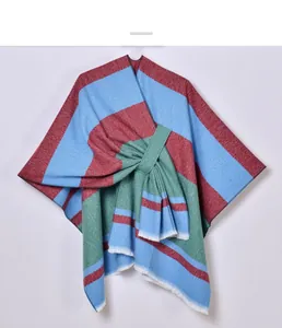 Detail of multi-color striped knitted poncho featuring tassel hem and knotted tie closure