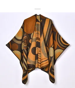 Detail of knitted poncho featuring brown and orange abstract geometric stripe patterns