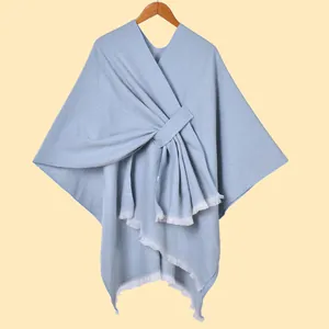 Detailed close-up of light blue knit shawl featuring white fringe trim and texture
