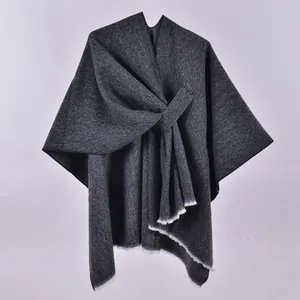 Detail of dark grey knit shawl featuring intricate textures and white fringe hemline