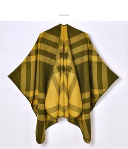 Detailed close-up of dark olive and yellow plaid knit cape with refined edge stitching