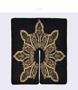Macro detail of black knitted cape featuring golden paisley jacquard and center slit