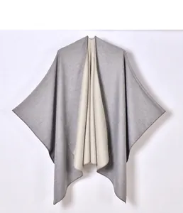 Detail of grey and beige reversible cashmere poncho with side split and soft texture