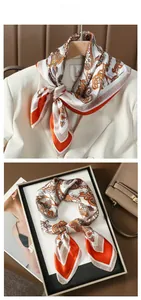 Détail d'un foulard en soie cachemire avec bordures géométriques sur plateau et blazer