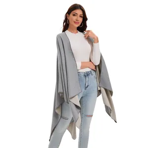 Detail of grey and beige reversible knitted shawl cape on a female model with jeans