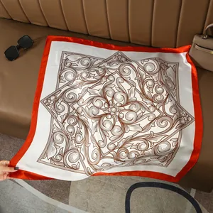 Detail of vintage patterned silk scarf with orange borders on a leather sofa surface