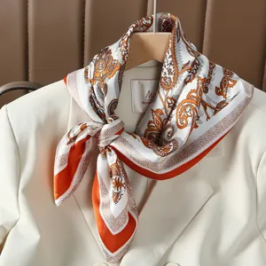 Foulard élégant en soie orange à motif paisley noué sur un blazer blanc style chic