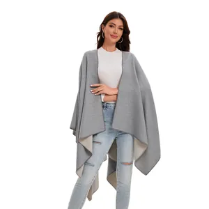 Detail view of a gray and beige reversible knit poncho shawl with an open-front design