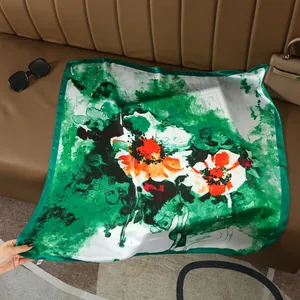 Close-up of emerald green silk scarf with floral patterns and soft drape texture