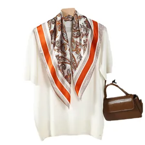 Foulard en soie vintage orange à motif Paisley drapé sur un tricot blanc élégant
