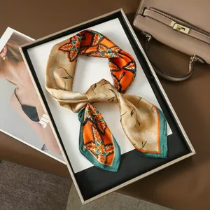 Elegant silk-like floral scarf in orange and green displayed on a gold tray for business style