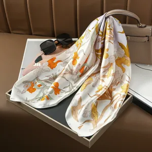 Dettaglio di un lussuoso foulard in seta con eleganti fiori arancioni su tessuto crema