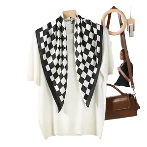 Elegant black and white checkerboard silk scarf with satin finish on white knit top
