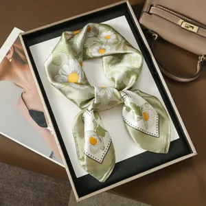 Elegant green silk square scarf with white daisy floral print and satin finish on a display