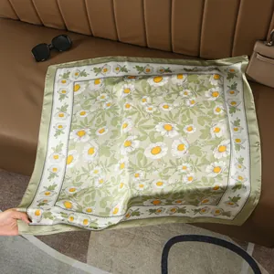 Detail of olive green floral silk scarf with daisy pattern on a leather background