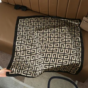 Detail of silk-feel square scarf with gold geometric patterns on a brown leather background