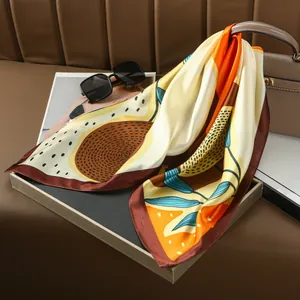 Abstract silk scarf with botanical prints and orange tones draped on a leather seat