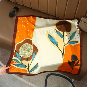 Detail of floral silk scarf with bold geometric patterns on a brown leather surface