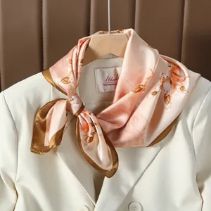 Carré de soie rose à imprimé floral et bordure contrastée sur un blazer blanc