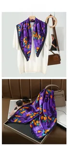 Detail of silk scarf with purple ginkgo print and navy border on a white knit top