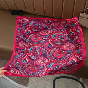 Detail of luxurious paisley silk square scarf with vibrant fuchsia patterns on leather