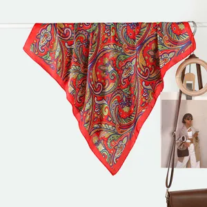 Elegant red paisley silk scarf with satin finish displayed in a lifestyle setting