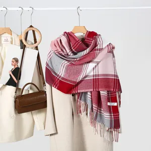 Long plaid scarf with red and pink patterns and tassels on a stylish beige coat