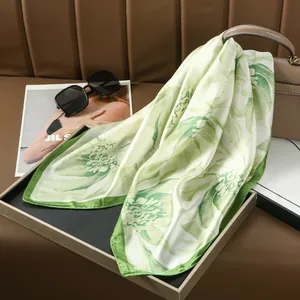 Elegant floral print silk scarf in green and white draped over a leather handbag