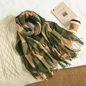 Detail of soft green plaid cashmere scarf with tassels on a white cable knit sweater