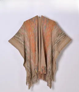 Détail d'un châle tricoté avec des rayures colorées et des franges à pompons bohèmes