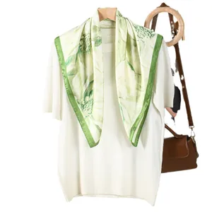 Light green floral silk scarf on a wooden hanger with cream blossom prints and dark green border