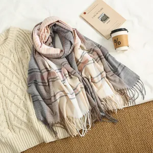 Flat lay of a cozy striped cashmere-like scarf with tassels next to a coffee cup
