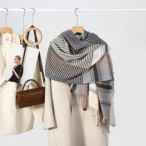 Detail of grey and beige plaid scarf with tassels styled on a wool coat and leather bag