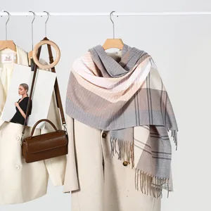 Winter striped fringe scarf in soft grey and pink tones draped over a beige wool coat