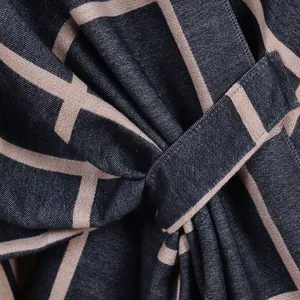 Dettaglio macro dello scialle in maglia blu scuro con righe geometriche beige e lacci