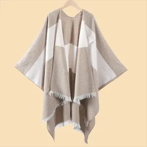Detailansicht der dicken Strickstruktur und weißen Fransen am beigen Kaschmir-Poncho