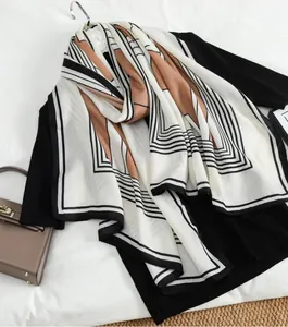 Detail of elegant beige scarf with geometric lines layered on a black top