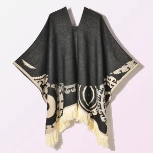 Close-up of ethnic geometric patterns and fine fringe detail on a warm knitted poncho