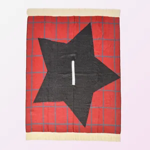 Detail of red and blue checkered knit shawl with grey star motif and cream fringe