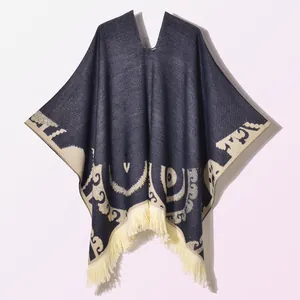 Detailed knit texture of navy blue and cream poncho with tassel edges and jacquard pattern