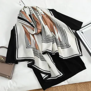 Elegant geometric silk scarf with black and caramel lines on a minimalist white backdrop