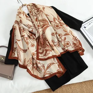 Nahaufnahme eines beigen Samtschals mit Blumenmuster, kombiniert mit Accessoires
