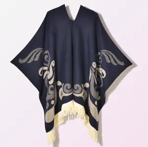 Detailed close-up of ethnic jacquard pattern and fringe on dark blue knit poncho