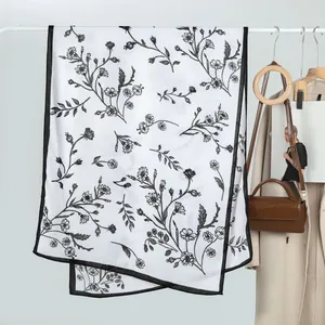Detail of floral chiffon shawl with elegant botanical print and delicate black hemmed edges