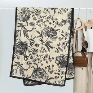 Detail eines bedruckten Seidenschals mit schwarzem Blumenmuster auf Creme