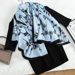 Light blue floral knit long scarf for women with black trim on elegant dress background
