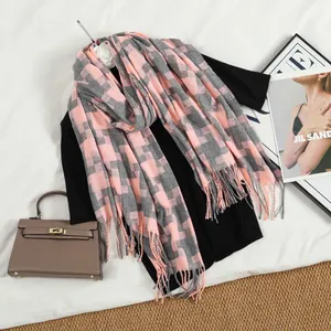Detail of pink and grey houndstooth scarf with fine tassel edges on a minimalist background