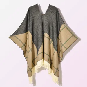 Detail of knit poncho featuring color-block patterns and cream tassel fringe trim