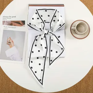 Elegante witte zijdeachtige smalle sjaal met zwarte stippen en puntige uiteinden op tafel