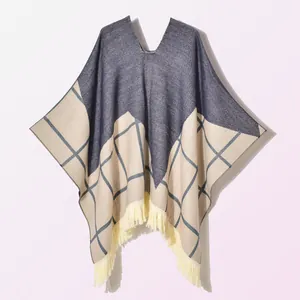 Detailed view of color-block poncho with beige tassels and large check pattern